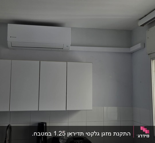 מזגן מותקן במטבח עם ארונות לבנים
